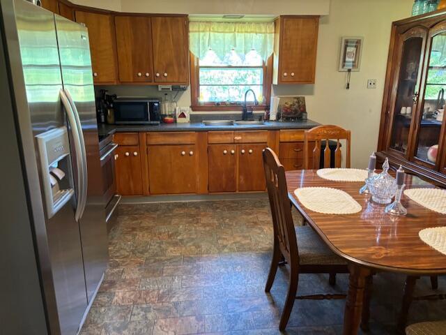 54 Kelley Rd, Mckee, KY 40447 - kitchen featuring stainless steel appliances, brown cabinetry, dark countertops, a sink, and stone finish flooring