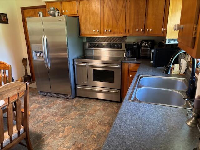 54 Kelley Rd, Mckee, KY 40447 - kitchen with appliances with stainless steel finishes, a sink, brown cabinets, dark countertops, and stone finish flooring