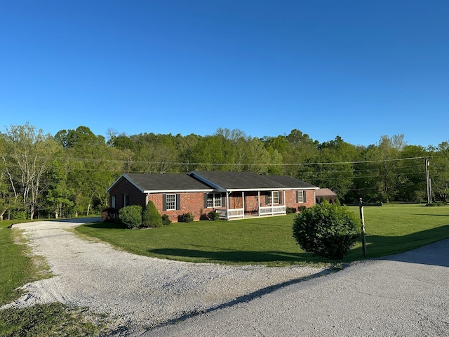 7532 Maysville Rd, Carlisle, KY 40311 - ranch-style home with brick siding, a porch, gravel driveway, a front lawn, and a wooded view