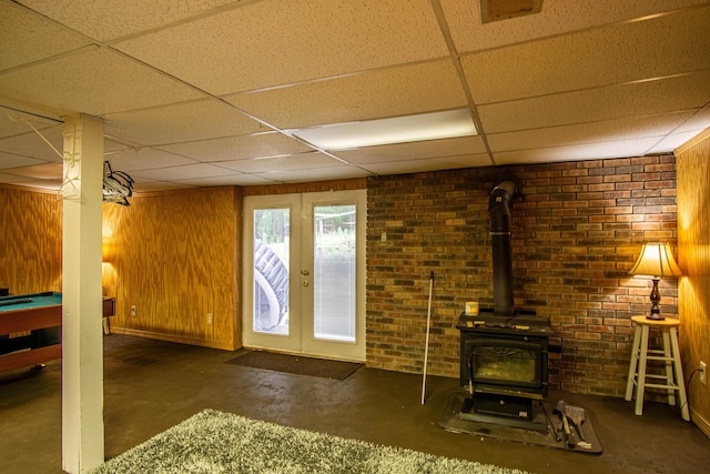 1540 Stoney Fork Rd, Corbin, KY 40701 - unfurnished living room featuring a paneled ceiling, a wood stove, concrete floors, french doors, and wood walls