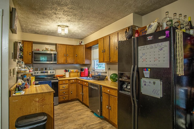 1540 Stoney Fork Rd, Corbin, KY 40701 - kitchen featuring stainless steel appliances, a textured ceiling, brown cabinetry, a sink, and light countertops
