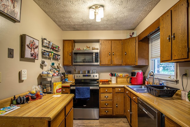 1540 Stoney Fork Rd, Corbin, KY 40701 - kitchen featuring stainless steel appliances, a sink, butcher block countertops, brown cabinetry, and a textured ceiling