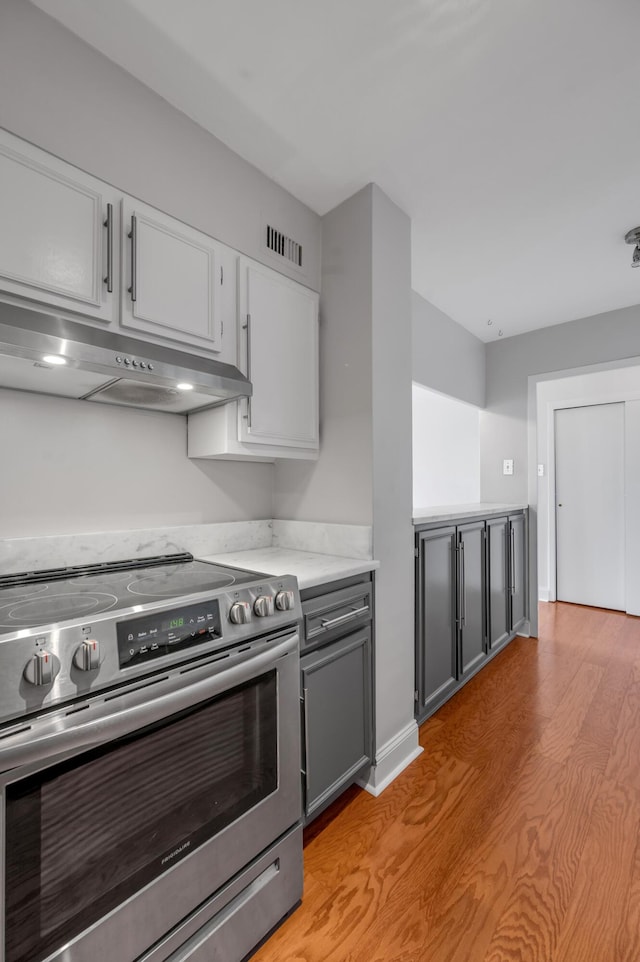 2121 Nicholasville Rd Unit 910, Lexington, KY 40503 - kitchen with stainless steel electric stove, under cabinet range hood, light wood-style flooring, light countertops, and white cabinets