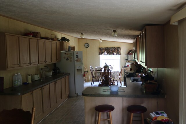 164 Oxbow Rd, Carlisle, KY 40311 - kitchen featuring white fridge with ice dispenser, a kitchen bar, dark countertops, a peninsula, and lofted ceiling