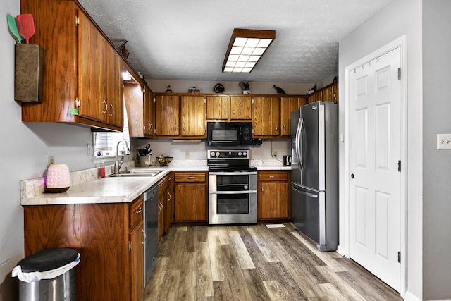 400 Aspen Dr, Lawrenceburg, KY 40342 - kitchen with stainless steel appliances, brown cabinetry, light wood-type flooring, and a textured ceiling
