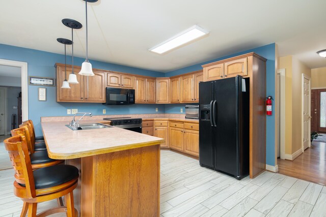 202 Thoroughbred Ln, Nicholasville, KY 40356 - kitchen with black appliances, a sink, a breakfast bar area, a peninsula, and hanging light fixtures