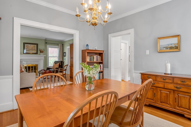 406 Dudley Rd, Lexington, KY 40502 - dining space with crown molding, light wood finished floors, a chandelier, a brick fireplace, and wainscoting