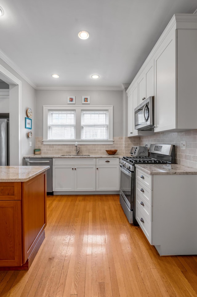 406 Dudley Rd, Lexington, KY 40502 - kitchen with appliances with stainless steel finishes, a sink, crown molding, light wood-style flooring, and tasteful backsplash