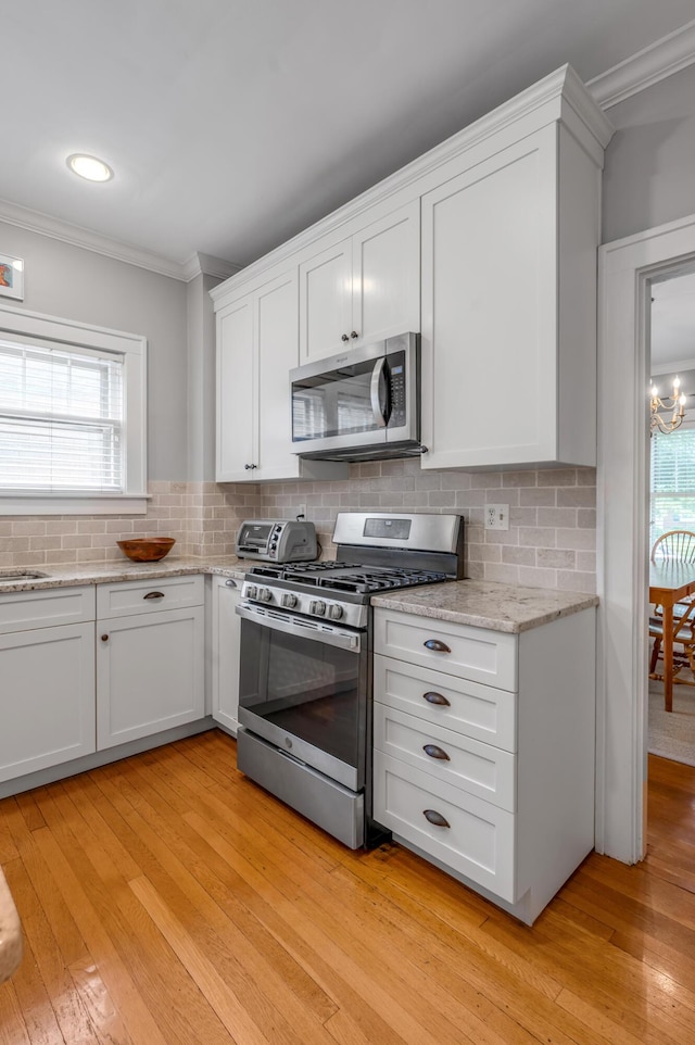 406 Dudley Rd, Lexington, KY 40502 - kitchen with appliances with stainless steel finishes, ornamental molding, light wood-type flooring, white cabinets, and tasteful backsplash