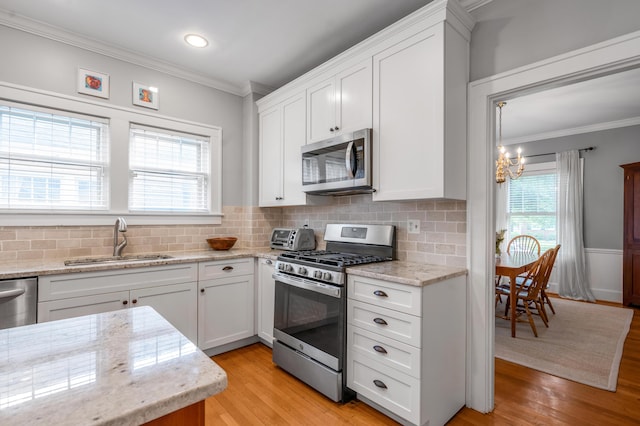 406 Dudley Rd, Lexington, KY 40502 - kitchen with stainless steel appliances, a sink, ornamental molding, a chandelier, and white cabinetry