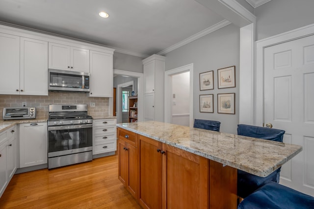 406 Dudley Rd, Lexington, KY 40502 - kitchen featuring stainless steel appliances, crown molding, light wood finished floors, backsplash, and white cabinetry
