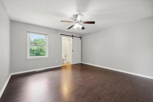 966 Jairus Dr, Lexington, KY 40515 - unfurnished bedroom featuring a barn door, baseboards, dark wood-style flooring, ensuite bathroom, and ceiling fan