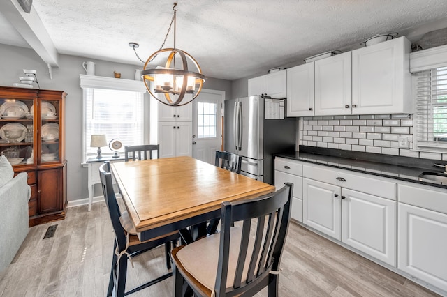 208 Westmoreland Ct, Georgetown, KY 40324 - dining room with a chandelier, light wood finished floors, healthy amount of natural light, a textured ceiling, and baseboards