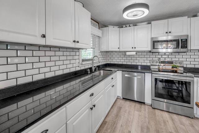208 Westmoreland Ct, Georgetown, KY 40324 - kitchen with stainless steel appliances, a sink, white cabinetry, light wood-type flooring, and a textured ceiling