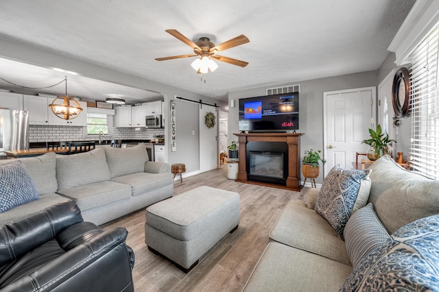 208 Westmoreland Ct, Georgetown, KY 40324 - living room featuring light wood-style flooring, a ceiling fan, a barn door, and baseboards