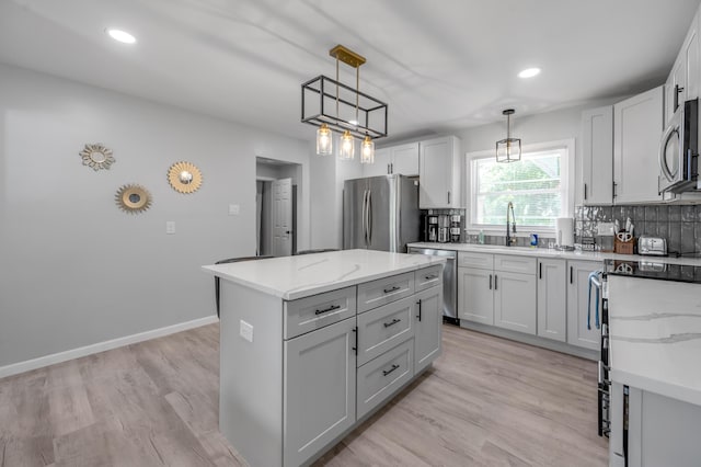 1626 Raleigh Rd, Lexington, KY 40505 - kitchen with appliances with stainless steel finishes, a kitchen island, hanging light fixtures, light stone counters, and decorative backsplash