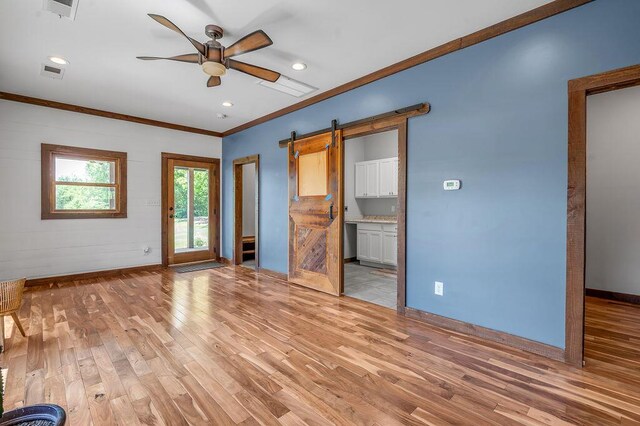 372 Sussex Ln, Nicholasville, KY 40356 - unfurnished living room featuring a barn door, light wood-style floors, ornamental molding, a ceiling fan, and baseboards