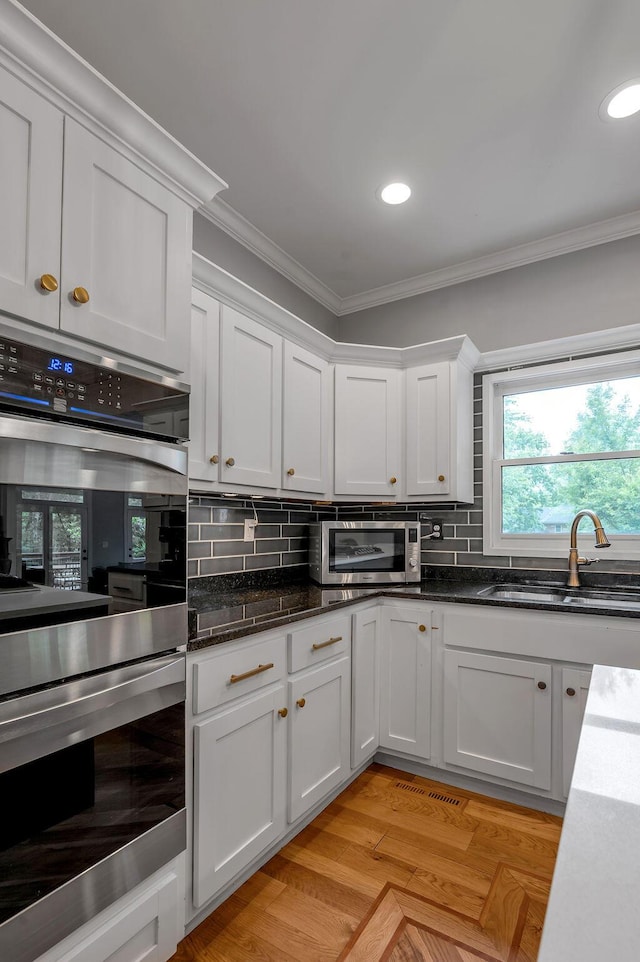 2245 Abbeywood Rd, Lexington, KY 40515 - kitchen featuring appliances with stainless steel finishes, a sink, crown molding, white cabinetry, and decorative backsplash