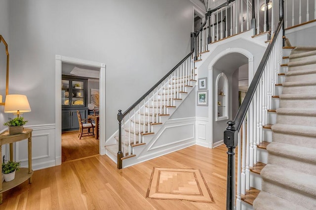 2245 Abbeywood Rd, Lexington, KY 40515 - staircase with arched walkways, a high ceiling, wood finished floors, a decorative wall, and a wainscoted wall