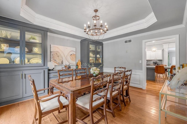 2245 Abbeywood Rd, Lexington, KY 40515 - dining space featuring a raised ceiling, a chandelier, light wood-type flooring, ornamental molding, and a decorative wall