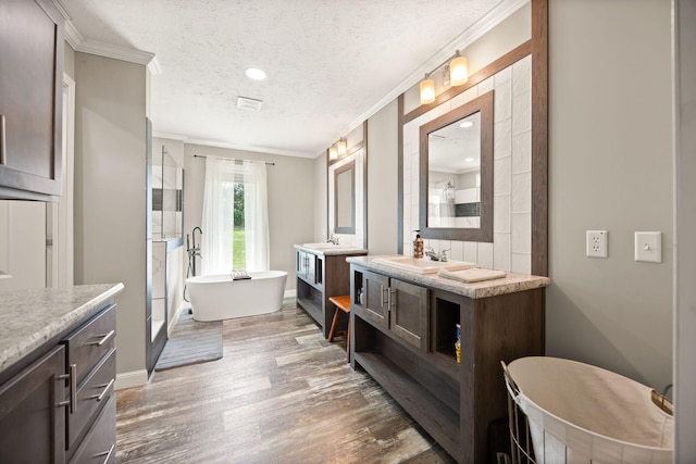 5483 US Highway 150 E, Stanford, KY 40484 - bathroom featuring two vanities, crown molding, wood finished floors, a freestanding tub, and a textured ceiling