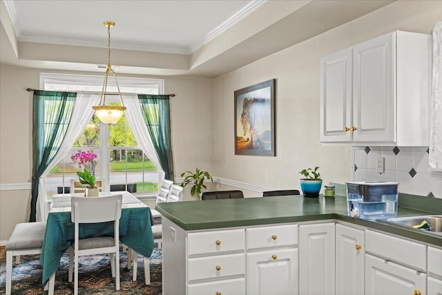 2713 Ella Rae Ct, Lexington, KY 40511 - kitchen featuring a peninsula, dark countertops, white cabinets, ornamental molding, and a tray ceiling
