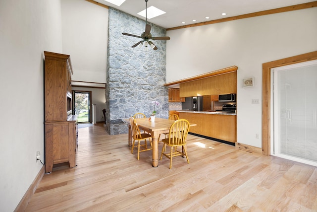 1636 Green Hill Estates Rd, Monticello, KY 42633 - dining area with a skylight, a high ceiling, light wood-type flooring, a ceiling fan, and baseboards