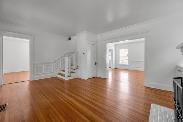 109 N Ashland Ave, Lexington, KY 40502 - unfurnished living room featuring stairs, a decorative wall, ornamental molding, wood finished floors, and a wainscoted wall