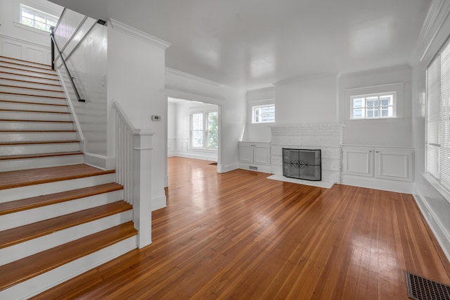 109 N Ashland Ave, Lexington, KY 40502 - unfurnished living room featuring hardwood / wood-style flooring, stairs, a fireplace, and crown molding