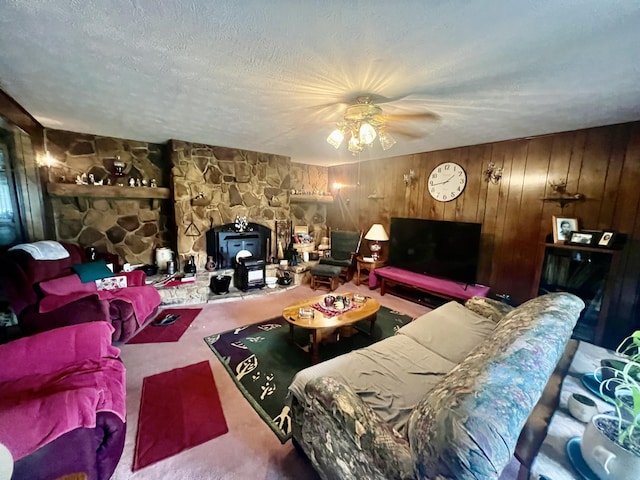 2369 Big Cave Rd, Mount Vernon, KY 40456 - living room with carpet floors, a wood stove, ceiling fan, wooden walls, and a textured ceiling