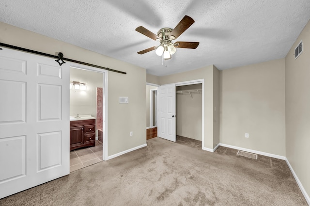 399 Stonecrest Rd, Winchester, KY 40391 - unfurnished bedroom with light colored carpet, a textured ceiling, baseboards, a barn door, and a closet