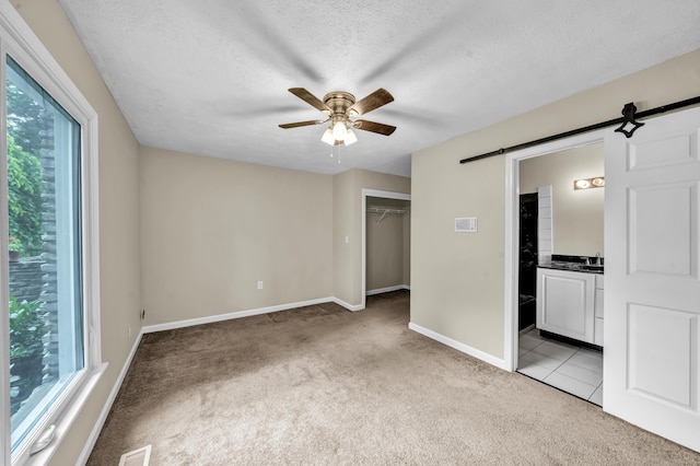 399 Stonecrest Rd, Winchester, KY 40391 - unfurnished bedroom with light colored carpet, a barn door, baseboards, a textured ceiling, and ensuite bath