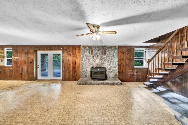 399 Stonecrest Rd, Winchester, KY 40391 - unfurnished living room with wood walls, stairway, a ceiling fan, a textured ceiling, and a wood stove