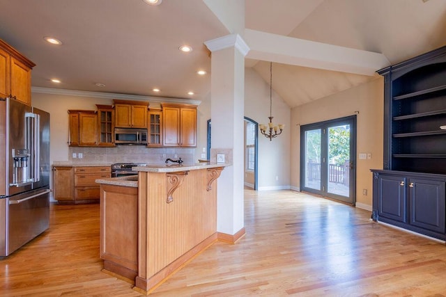 2433 San Milano Pl, Lexington, KY 40509 - kitchen featuring appliances with stainless steel finishes, brown cabinets, a kitchen bar, a chandelier, and a peninsula