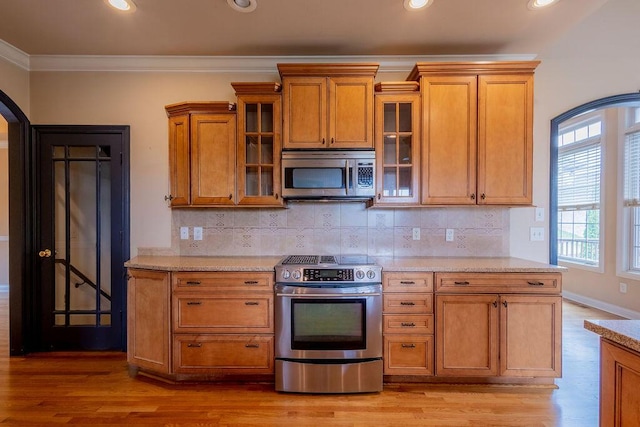 2433 San Milano Pl, Lexington, KY 40509 - kitchen with stainless steel appliances, brown cabinetry, decorative backsplash, ornamental molding, and light wood-style flooring