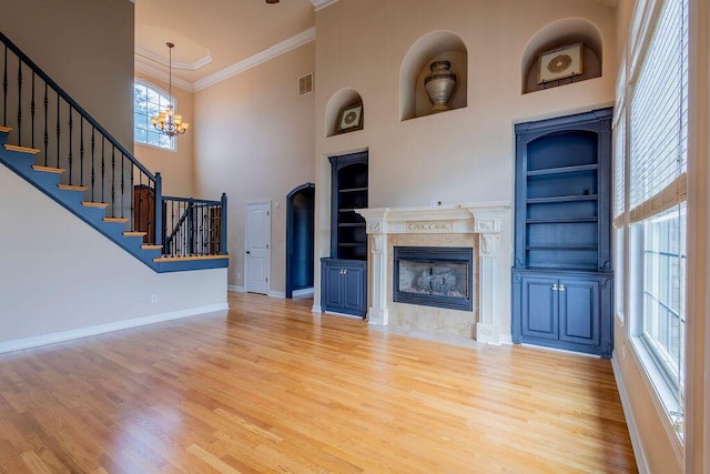 2433 San Milano Pl, Lexington, KY 40509 - unfurnished living room featuring built in shelves, ornamental molding, wood finished floors, a towering ceiling, and stairway
