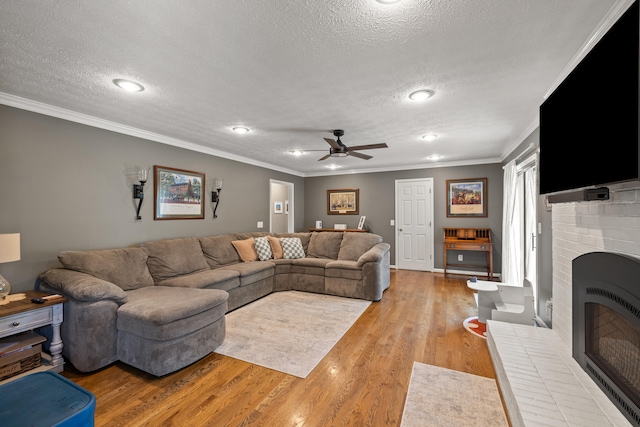 105 Wellington Cv, Danville, KY 40422 - living room featuring a textured ceiling, ceiling fan, light wood finished floors, crown molding, and a brick fireplace