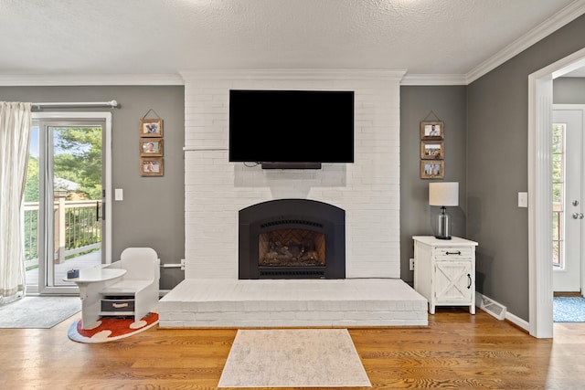 105 Wellington Cv, Danville, KY 40422 - living room with wood finished floors, a brick fireplace, a textured ceiling, ornamental molding, and baseboards