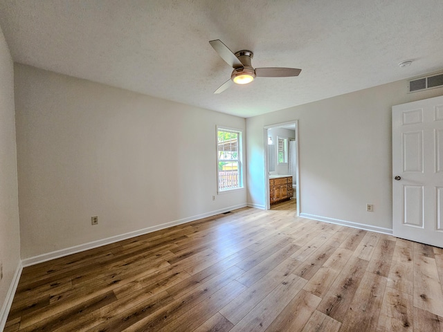 186 Amber Ln, Hustonville, KY 40437 - unfurnished bedroom featuring light wood-type flooring, baseboards, a textured ceiling, ensuite bath, and a ceiling fan