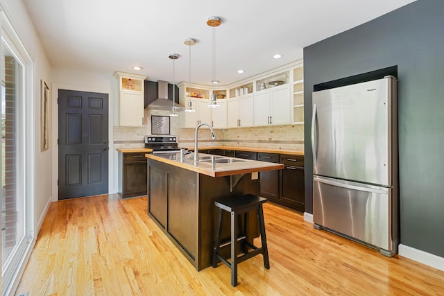 131 Reasor St, Corbin, KY 40701 - kitchen featuring appliances with stainless steel finishes, a sink, wall chimney range hood, decorative backsplash, and light wood-style floors