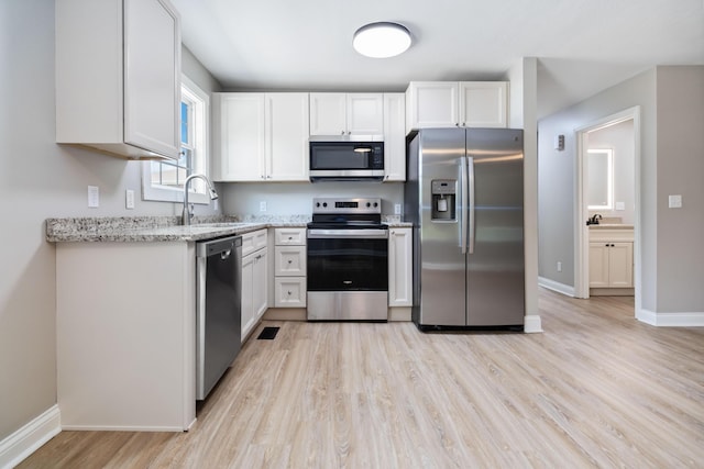 56 Hopewell Church Rd, Corbin, KY 40701 - kitchen featuring stainless steel appliances, a sink, light wood-style flooring, light stone countertops, and white cabinets