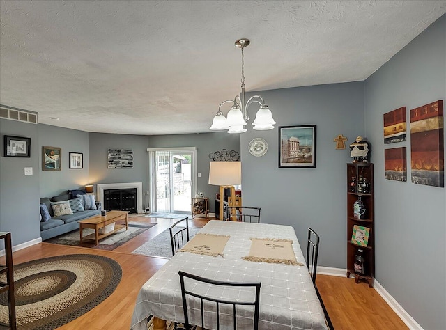 3471 Pimlico Pkwy Unit B, Lexington, KY 40517 - dining space with wood finished floors, a chandelier, baseboards, a textured ceiling, and a fireplace