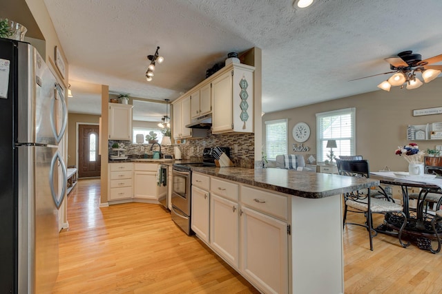 220 Mcdowell Dr, Winchester, KY 40391 - kitchen featuring appliances with stainless steel finishes, a peninsula, under cabinet range hood, plenty of natural light, and a textured ceiling