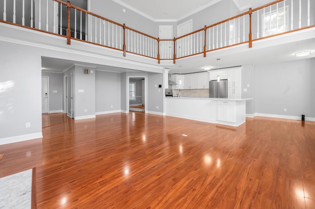 244 Chippendale Cir, Lexington, KY 40517 - unfurnished living room with a towering ceiling, baseboards, wood finished floors, crown molding, and a sink