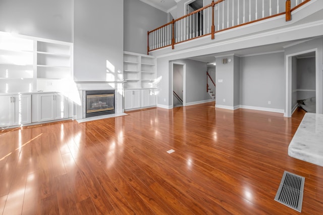 244 Chippendale Cir, Lexington, KY 40517 - unfurnished living room featuring a towering ceiling, built in features, stairway, ornamental molding, and wood finished floors