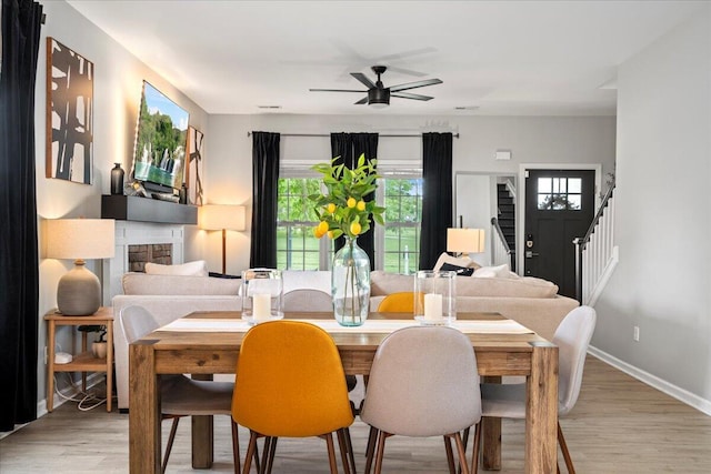 588 E Fifth St, Lexington, KY 40508 - dining space featuring stairs, ceiling fan, light wood finished floors, baseboards, and a fireplace