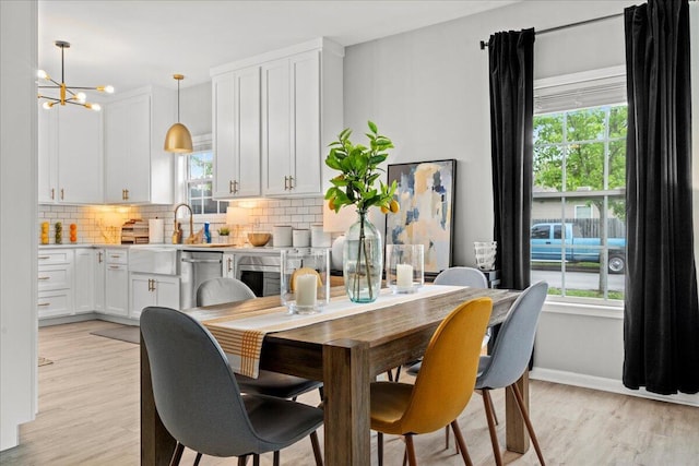 588 E Fifth St, Lexington, KY 40508 - dining room with healthy amount of natural light, light wood-type flooring, a chandelier, and baseboards