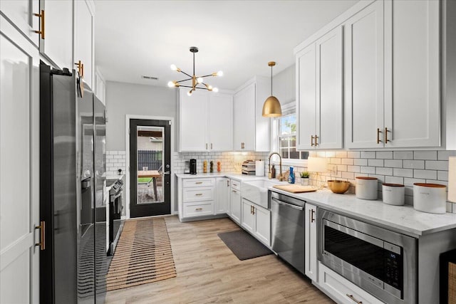588 E Fifth St, Lexington, KY 40508 - kitchen with appliances with stainless steel finishes, a chandelier, a sink, white cabinets, and tasteful backsplash