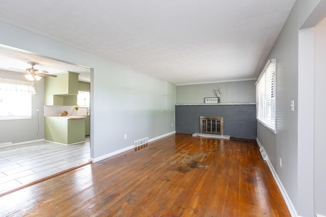 9581 Harrodsburg Rd, Wilmore, KY 40390 - unfurnished living room with plenty of natural light, a fireplace, wood-type flooring, and a ceiling fan
