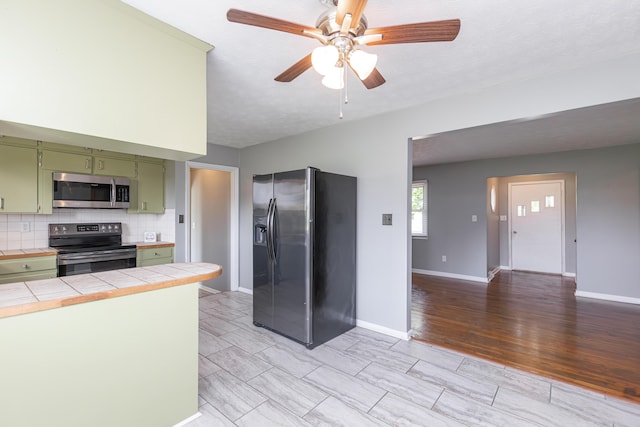 9581 Harrodsburg Rd, Wilmore, KY 40390 - kitchen with green cabinetry, stainless steel microwave, range with electric cooktop, refrigerator with ice dispenser, and tile countertops